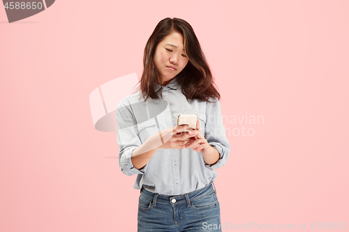 Image of Young beautiful woman using mobile phone studio on pink color background