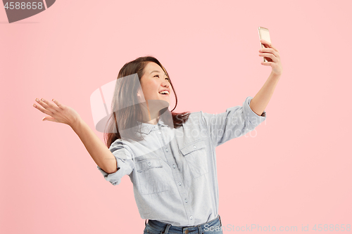 Image of Portrait of a happy smiling casual girl showing blank screen mobile phone isolated over pink background