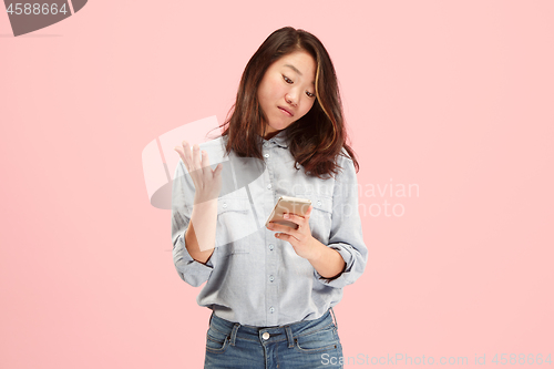 Image of Young beautiful woman using mobile phone studio on pink color background