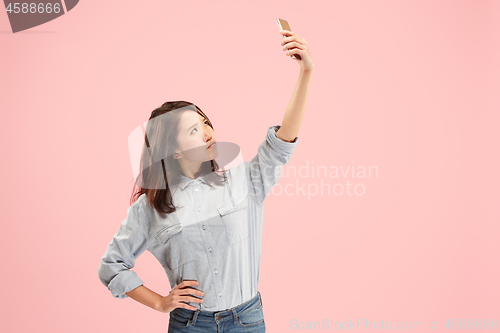 Image of Portrait of a happy smiling casual girl showing blank screen mobile phone isolated over pink background