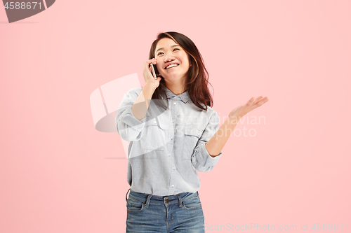 Image of Young beautiful woman using mobile phone studio on pink color background