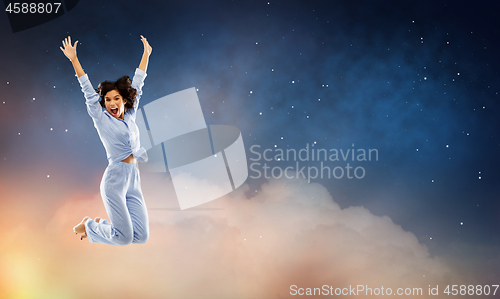 Image of happy woman in blue pajama jumping over night sky