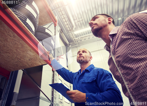 Image of auto mechanic and man with tires at car shop