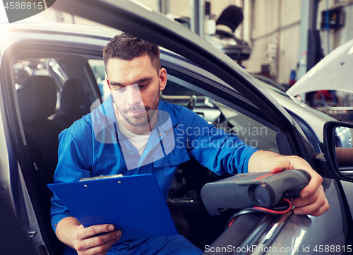 Image of mechanic man with diagnostic scanner at car shop