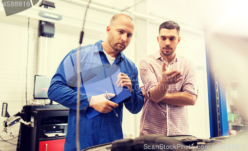 Image of auto mechanic with clipboard and man at car shop