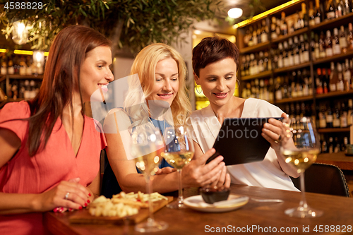 Image of women with tablet pc at wine bar or restaurant