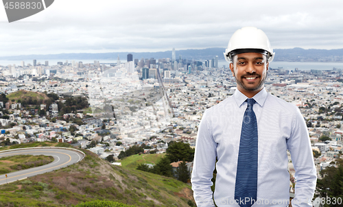 Image of architect or businessman in helmet over city