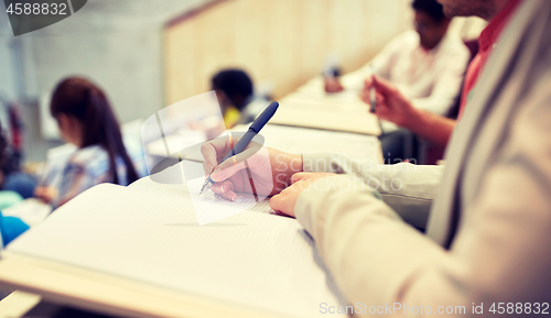 Image of student writing to notebook at exam or lecture