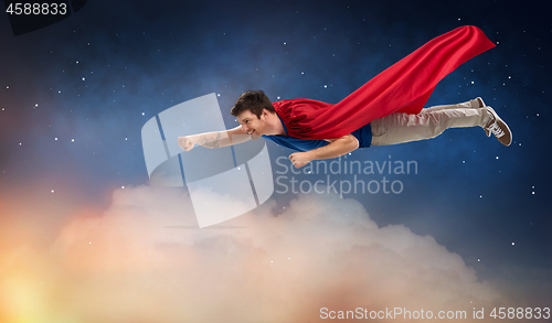 Image of man in red superhero cape flying over night sky