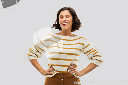 Image of smiling woman in pullover with hands on hips