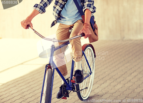 Image of young hipster man with bag riding fixed gear bike