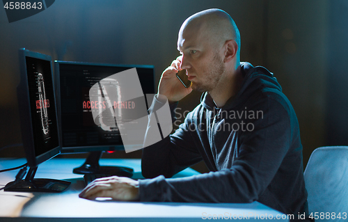 Image of hacker with no access on computer calls on cell