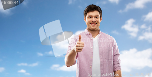 Image of happy young man showing thumbs up over blue sky