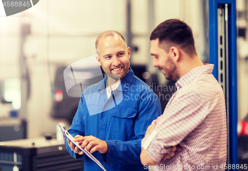 Image of auto mechanic with clipboard and man at car shop