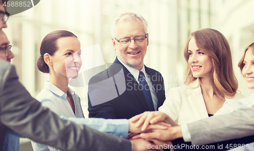 Image of business people putting hands on top in office