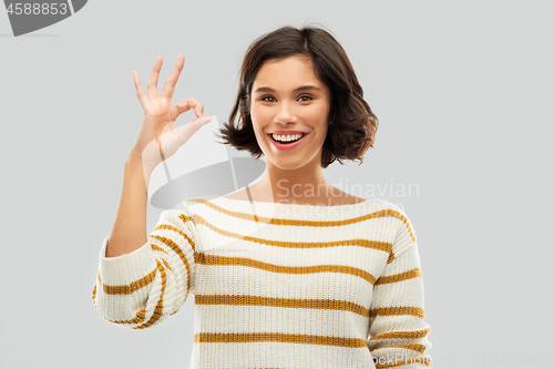 Image of happy smiling woman in striped pullover showing ok