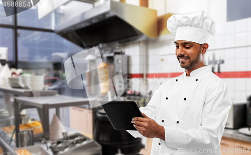 Image of male indian chef with tablet pc at kebab shop