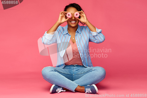 Image of happy african american woman with eyes of donuts