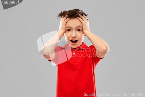 Image of shocked little boy in red t-shirt touching head