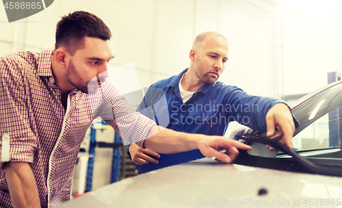 Image of auto mechanic with clipboard and man at car shop