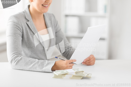 Image of businesswoman with tax form and money on table