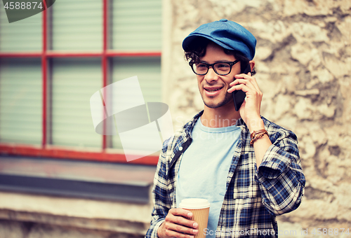 Image of man with coffee calling on smartphone in city