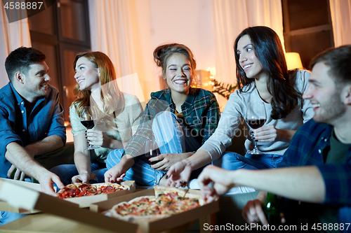 Image of friends eating pizza and drinking red wine at home