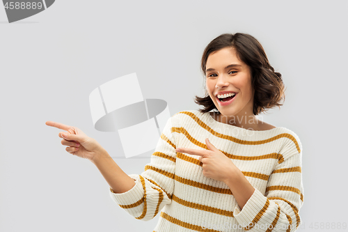 Image of happy smiling woman pointing fingers to something