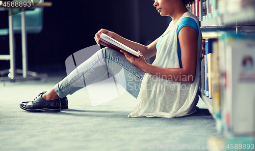 Image of happy african student girl reading book at library