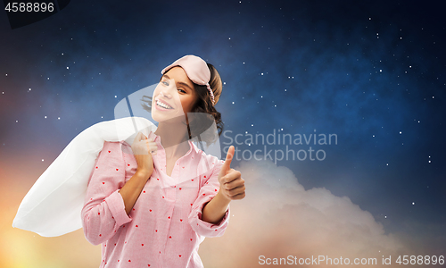 Image of woman with pillow in pajama showing thumbs up