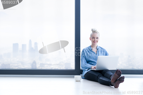 Image of woman drinking coffee and using laptop at home