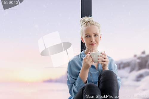 Image of woman drinking coffee and using laptop at home