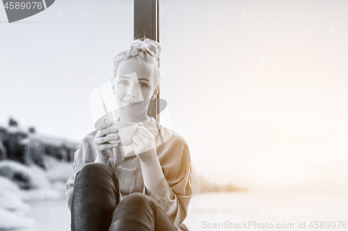 Image of woman drinking coffee and using laptop at home