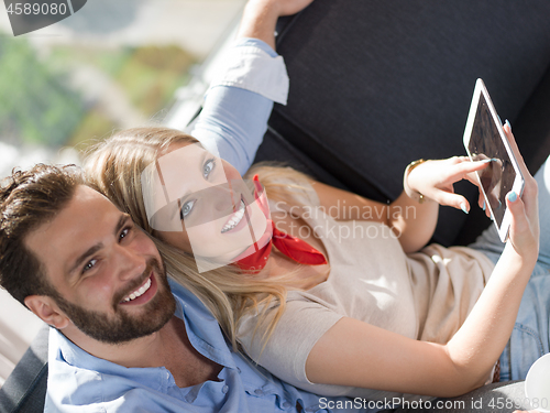 Image of couple relaxing at  home with tablet computers