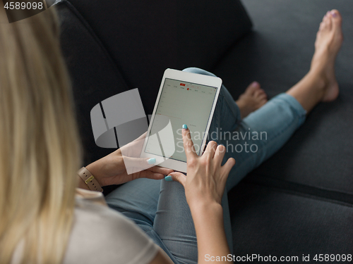 Image of young woman on sofa at home surfing web