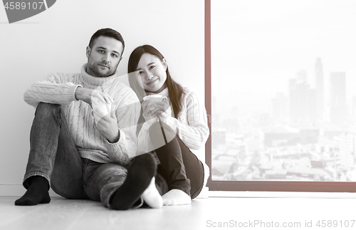 Image of multiethnic couple enjoying morning coffee by the window