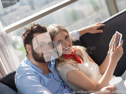 Image of couple relaxing at  home with tablet computers