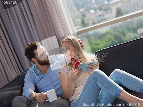 Image of couple relaxing at  home with tablet computers