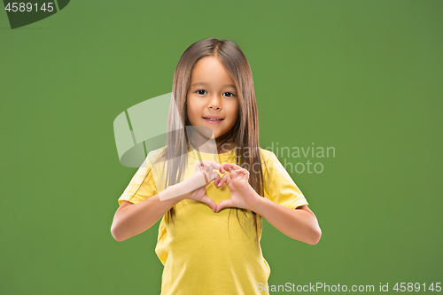 Image of Beautiful smiling teen girl makes the shape of a heart with her hands on the green background.