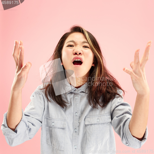 Image of The young emotional angry woman screaming on pink studio background