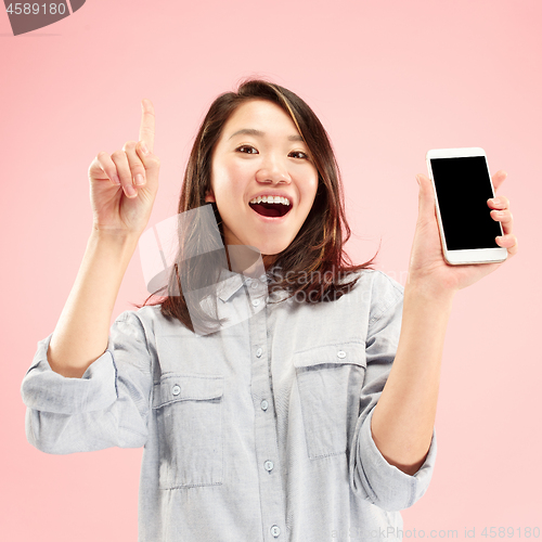 Image of Portrait of a confident casual girl showing blank screen mobile phone isolated over pink background