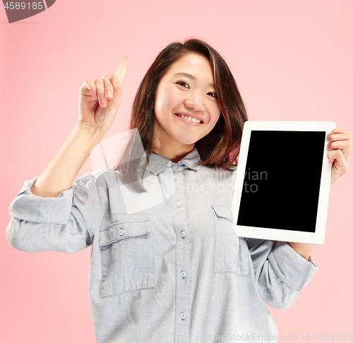 Image of Portrait of a confident casual girl showing blank screen of laptop isolated over pink background