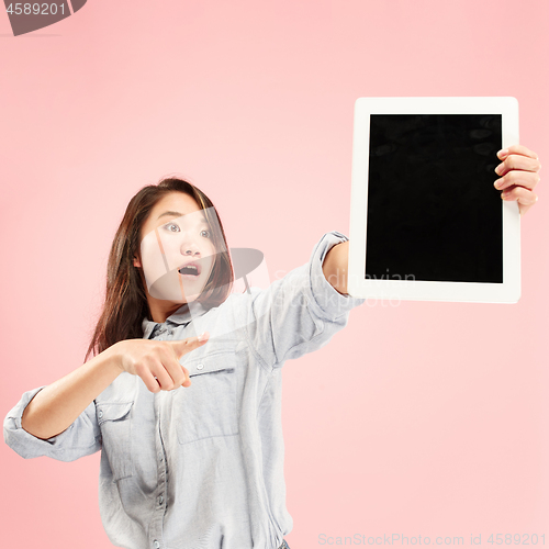 Image of Portrait of a confident casual girl showing blank screen of laptop isolated over pink background