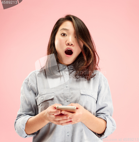 Image of Young beautiful woman using mobile phone studio on pink color background