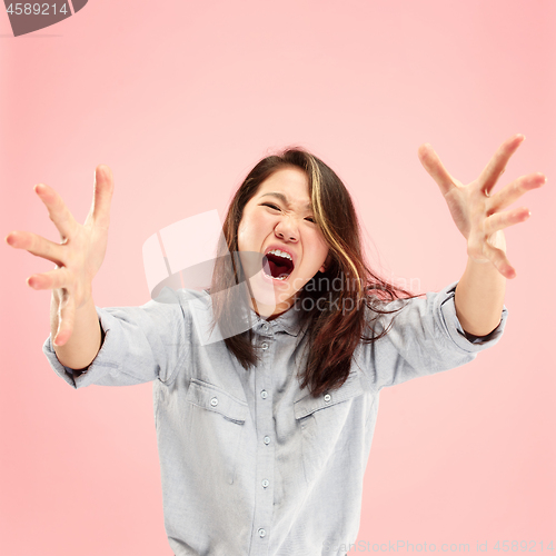 Image of The young emotional angry woman screaming on pink studio background