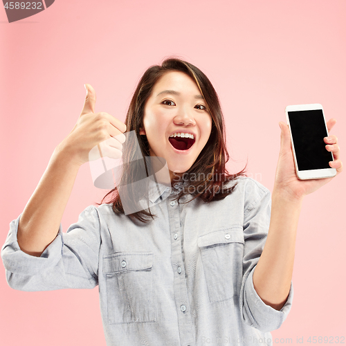 Image of Portrait of a confident casual girl showing blank screen mobile phone isolated over pink background