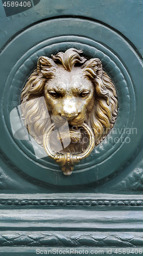 Image of Doorknocker with head of lion on a green wooden door