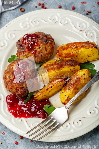 Image of Meat cutlets and baked potatoes with lingonberry sauce.