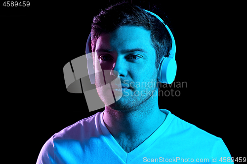 Image of man in headphones over neon lights of night club