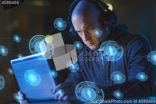 Image of hacker in headset typing on laptop in dark room